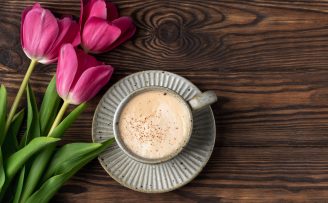 pink tulips, cup with coffee on a wooden background, copy space
